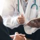 doctor wearing a white coat and stethoscope holding a clipboard